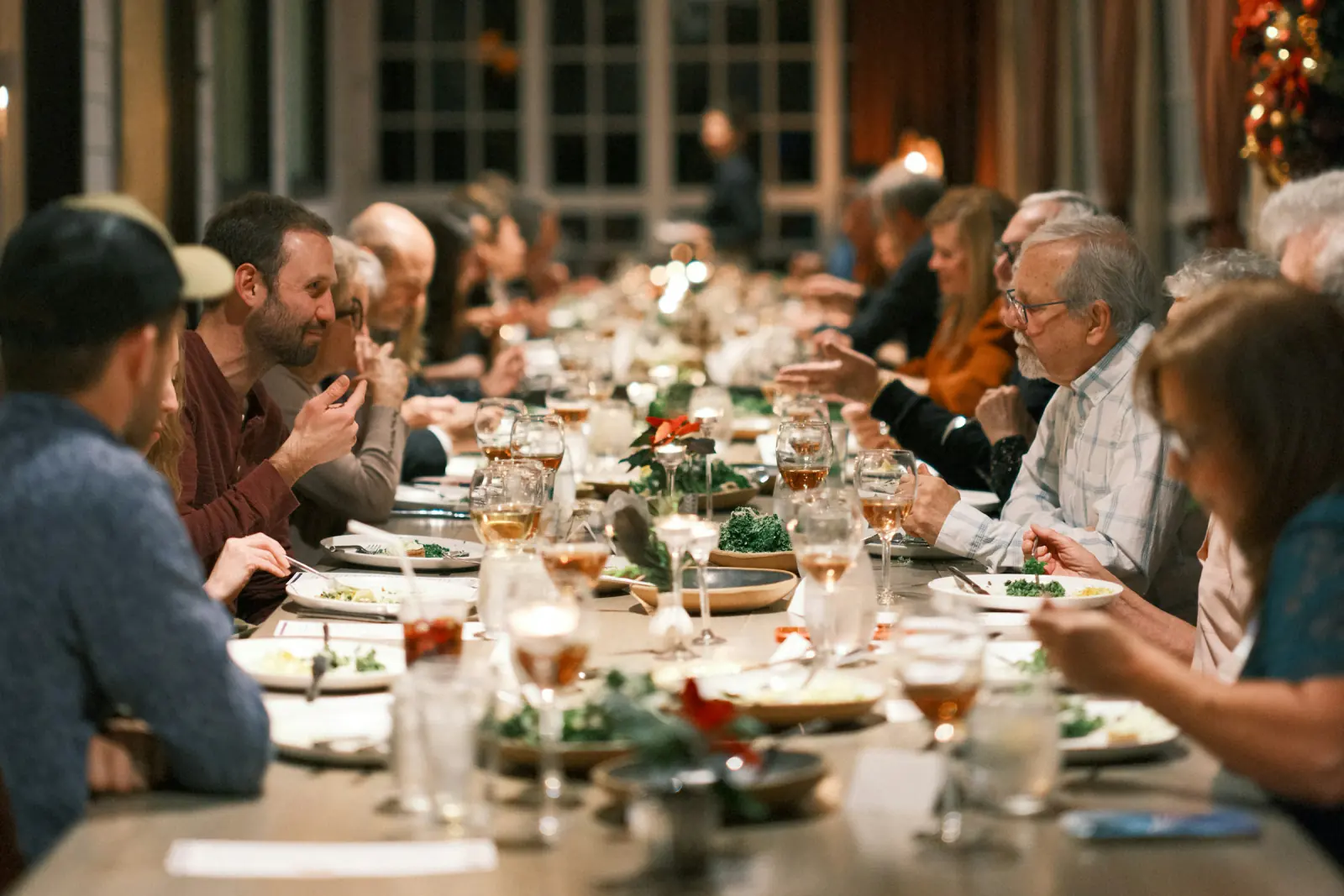 Colleagues at a long festive dinner table in a warmly lit restaurant