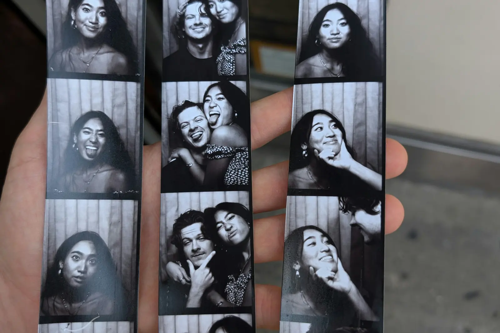 Hand holding three black-and-white photo booth strips